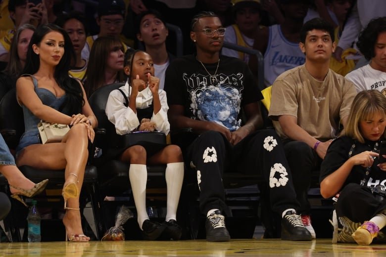 The front row of spectators are shown during a basketball game.