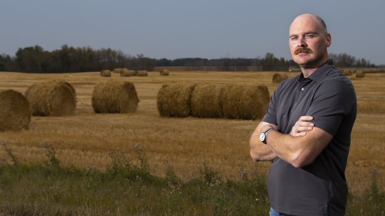 A man stands in front of a field.