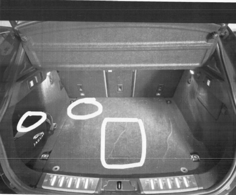 The trunk of a car with three white chalk drawings — one in the form of a box in the middle of the trunk and two in the form of white circles in the left front corner of the trunk.